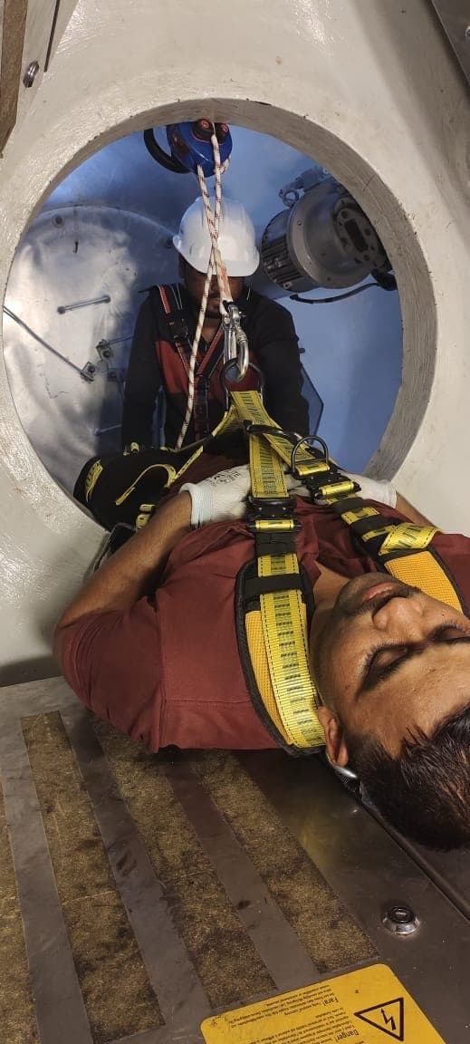 Volunteer casualty in a harness being recovered through a turbine opening during blade rescue training