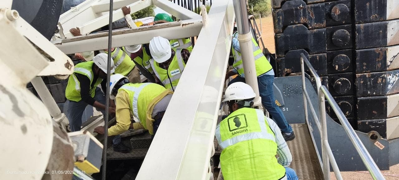 Participants in helmets and high-visibility vests working on crane and hoist equipment
