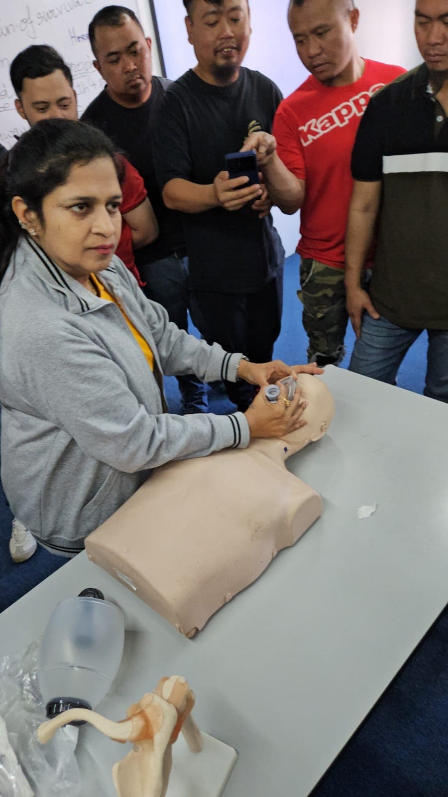 Trainer demonstrating airway techniques on a manikin to participants during an enhanced first aid session