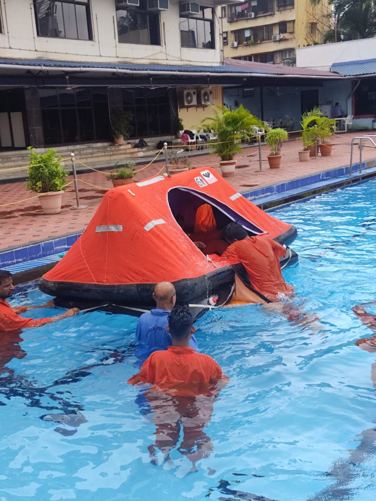 Participants boarding an inflatable life raft in a training pool during sea survival training
