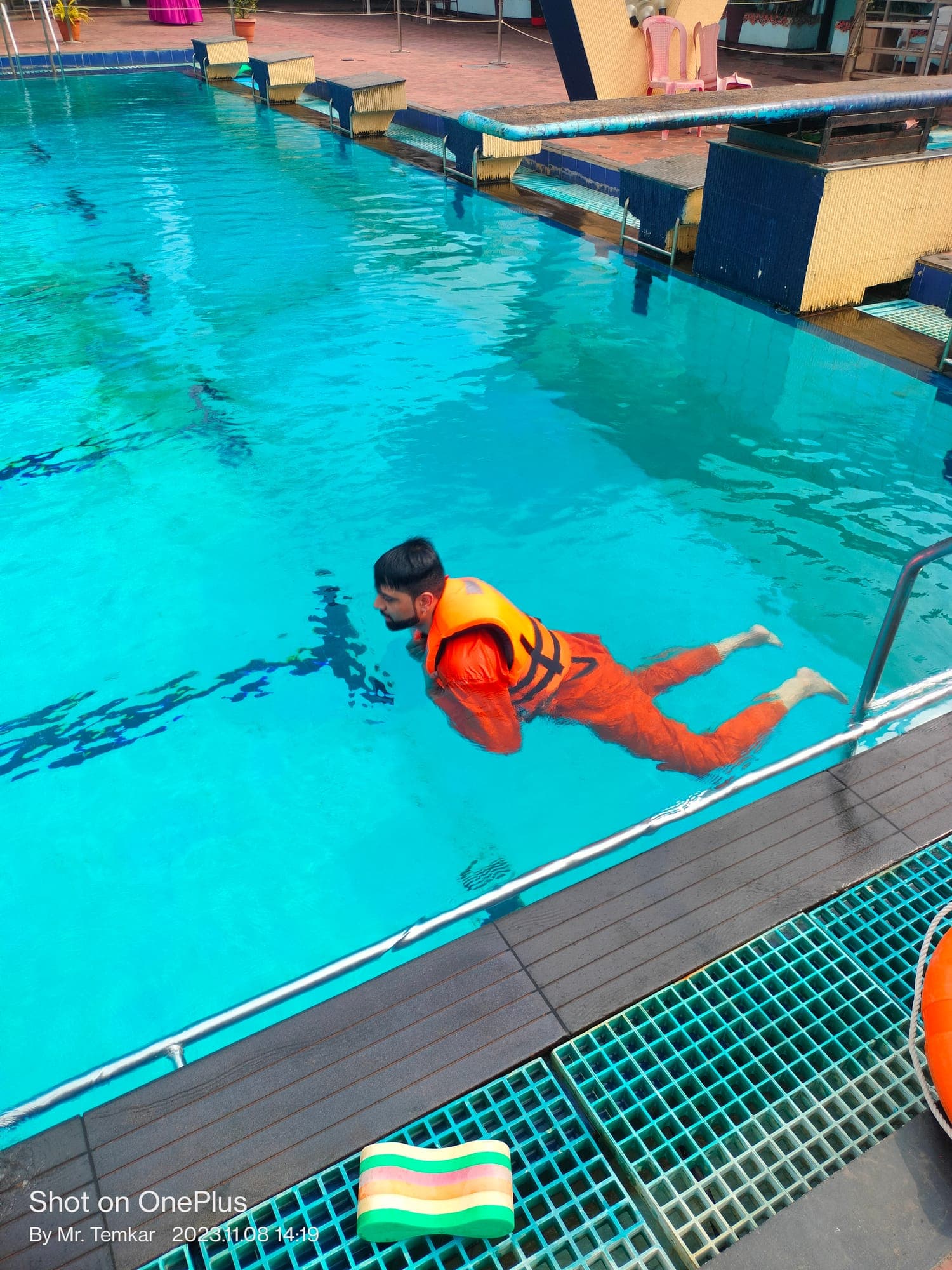 Participant in an immersion suit and lifejacket swimming in a training pool during sea survival training