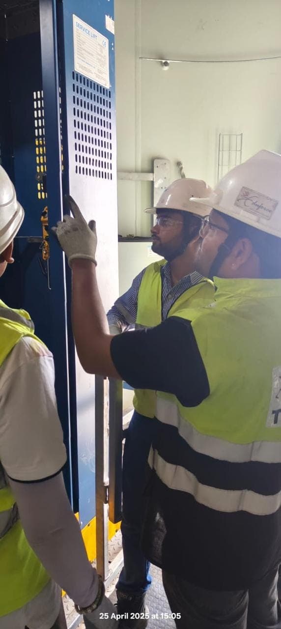 Technicians in helmets and high-visibility clothing working at a service lift inside a tower