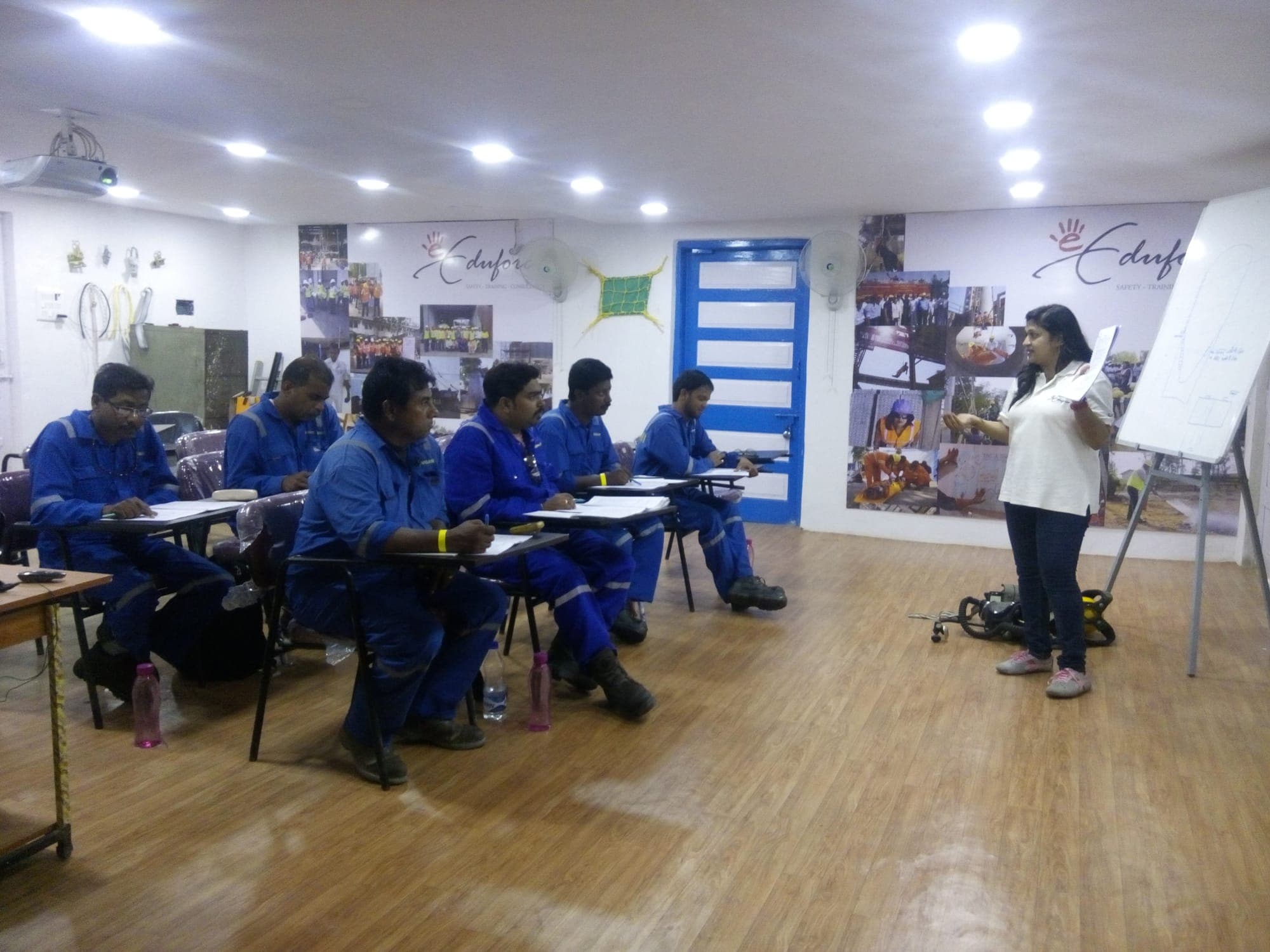 Participants seated at tables during an emergency response planning session, with the trainer at the front of the room