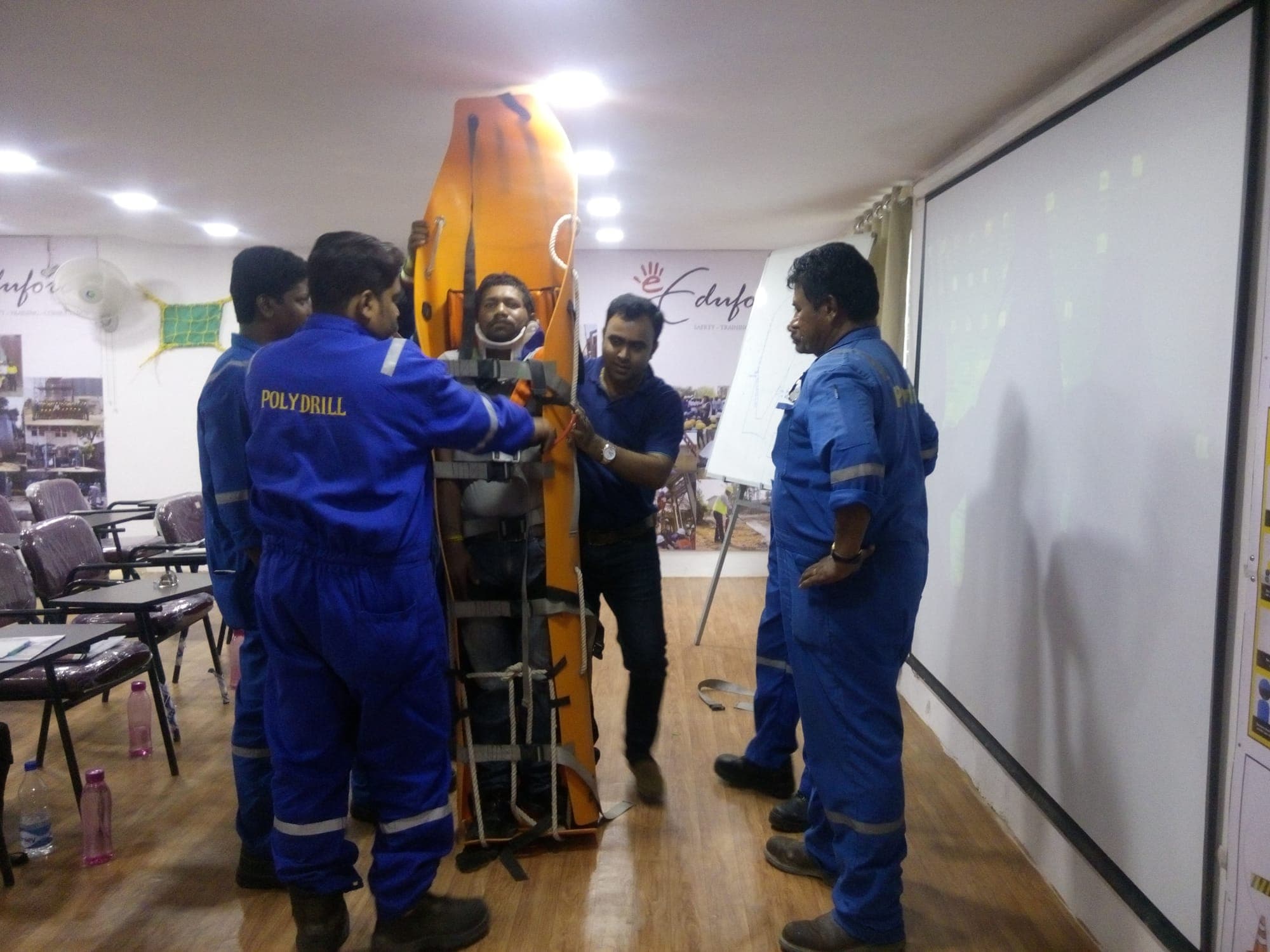 Participants holding a basket stretcher upright with a casualty secured inside