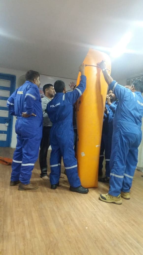 Participants supporting a basket stretcher held vertically during a lifting exercise