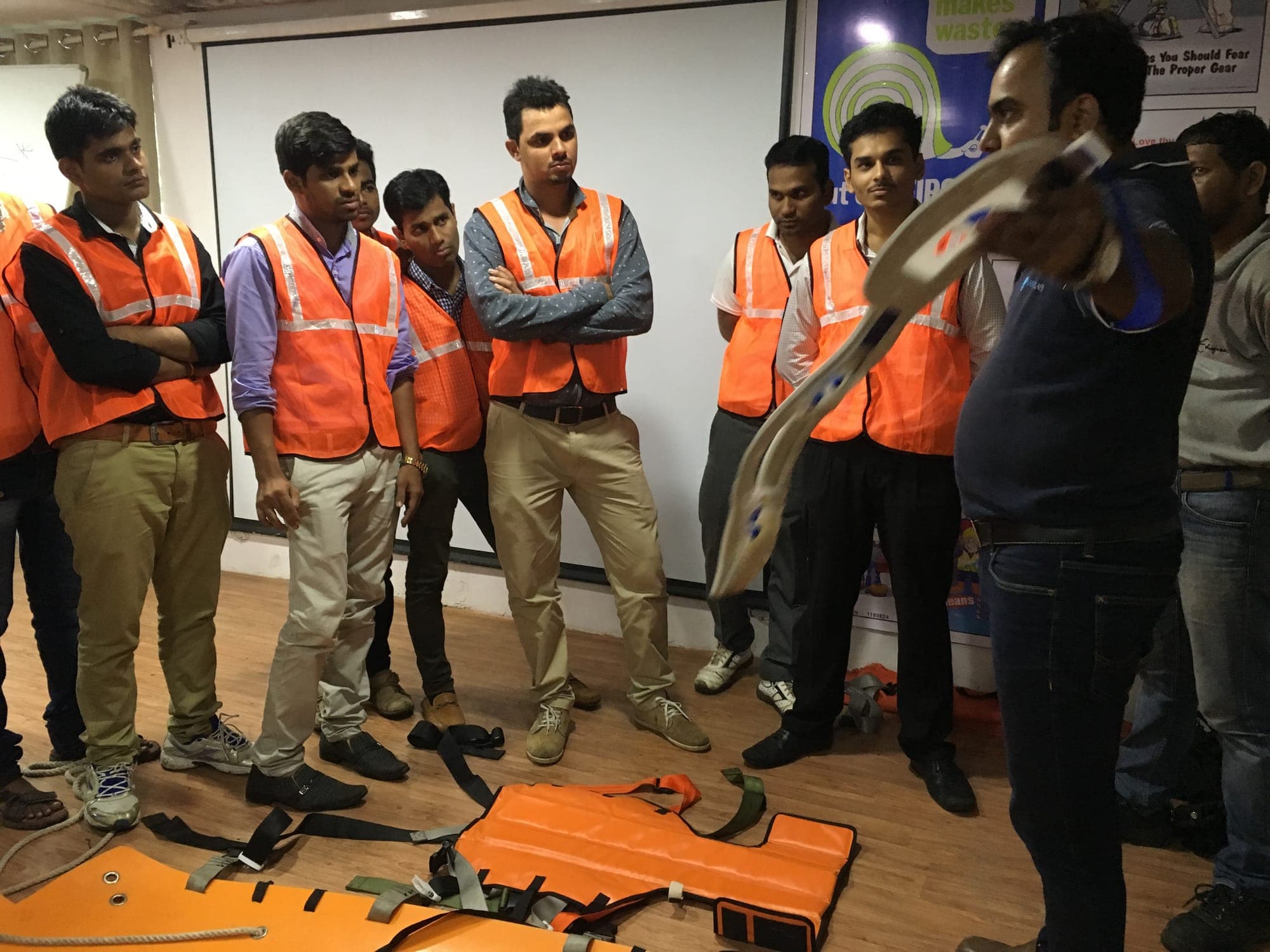 Trainer briefing participants in high-visibility vests with rescue equipment laid out on the floor
