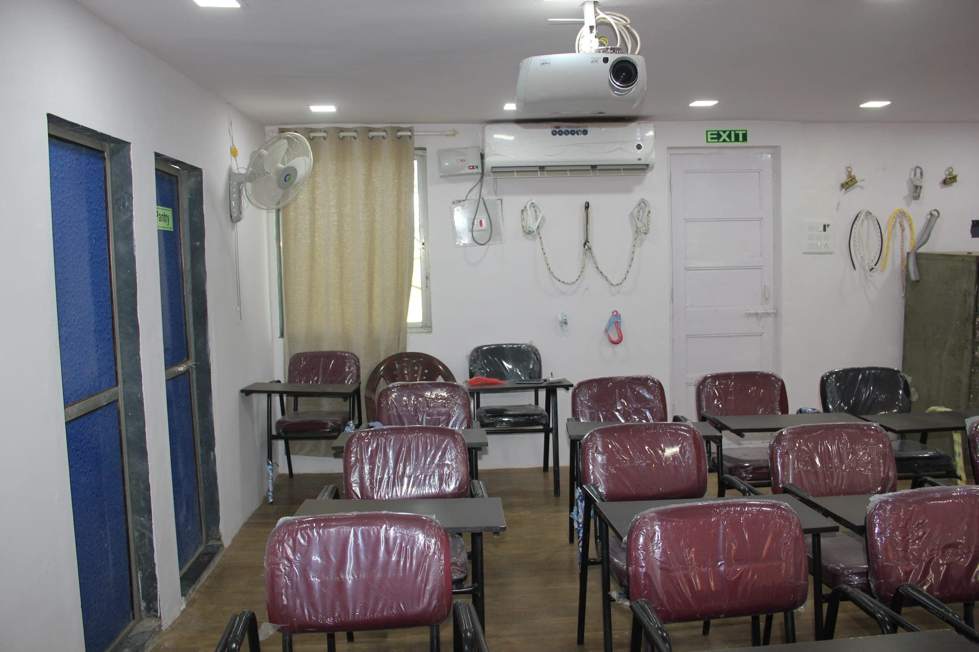 Training classroom with desks, chairs, a projector and rescue equipment on the wall