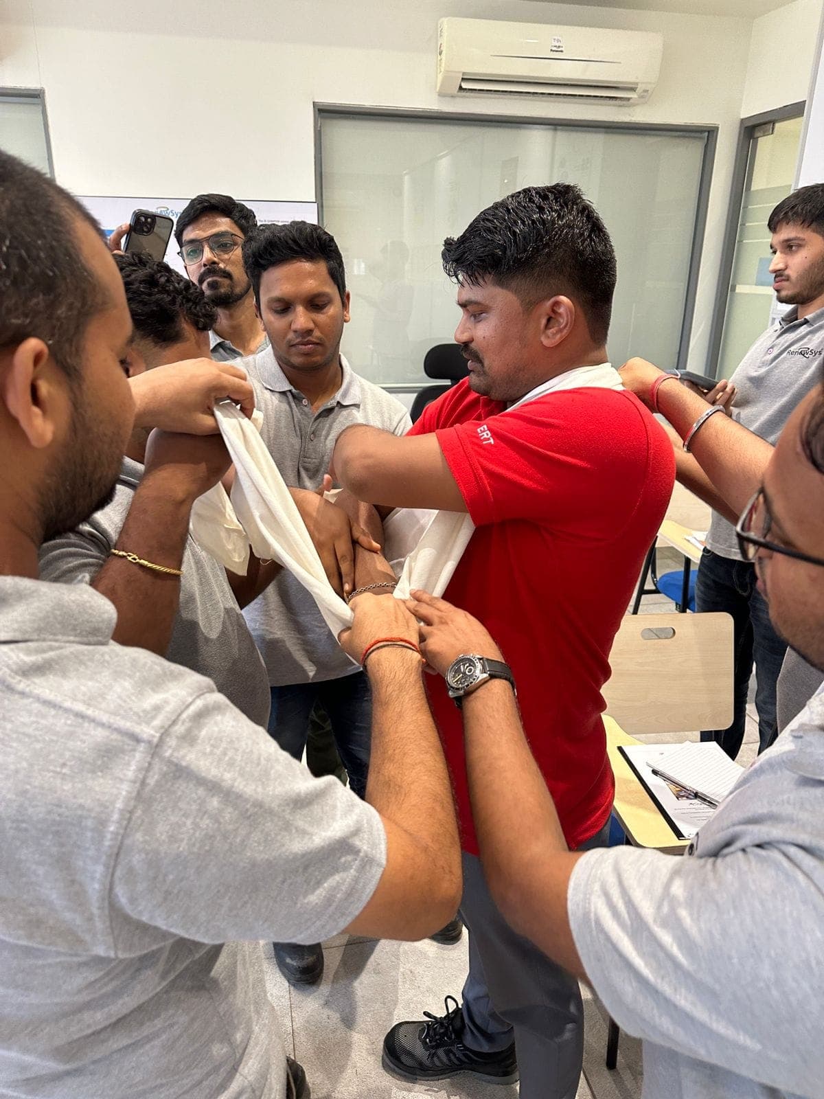 Participants applying an arm sling to a volunteer during a first aid session