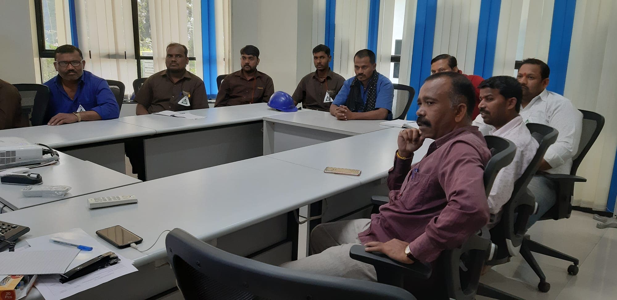 Participants in company uniform seated around a table during a behaviour based safety training session