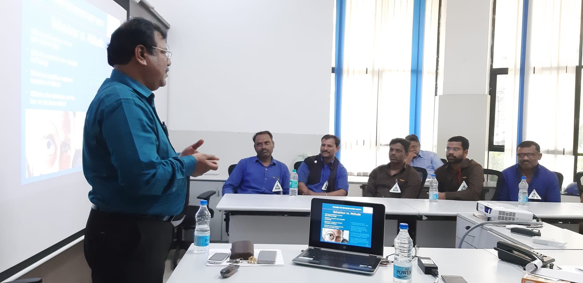 Wide view of a training room with participants seated around a conference table during a safety session