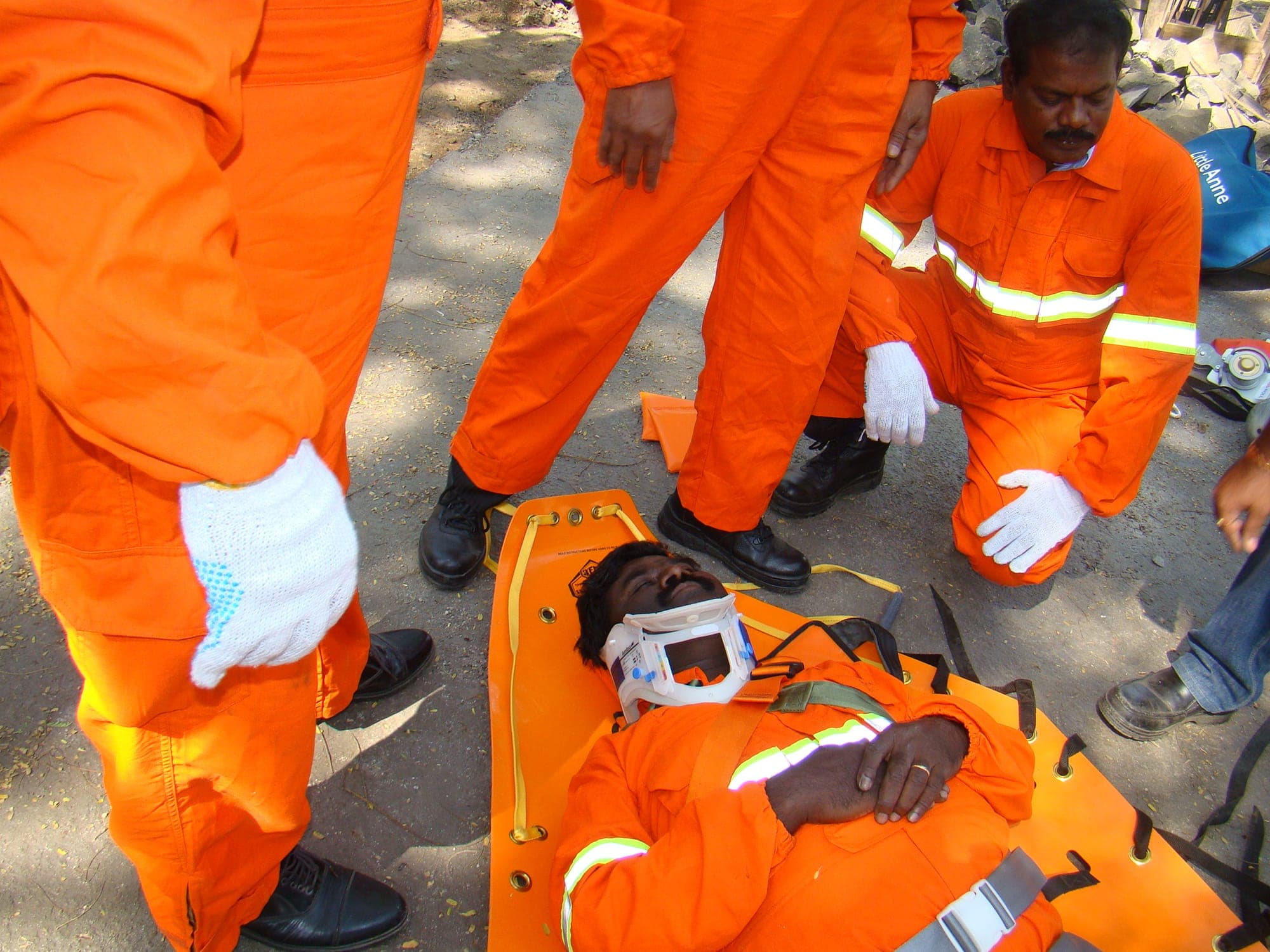 Participants practising immobilising a casualty on a spine board with a cervical collar fitted