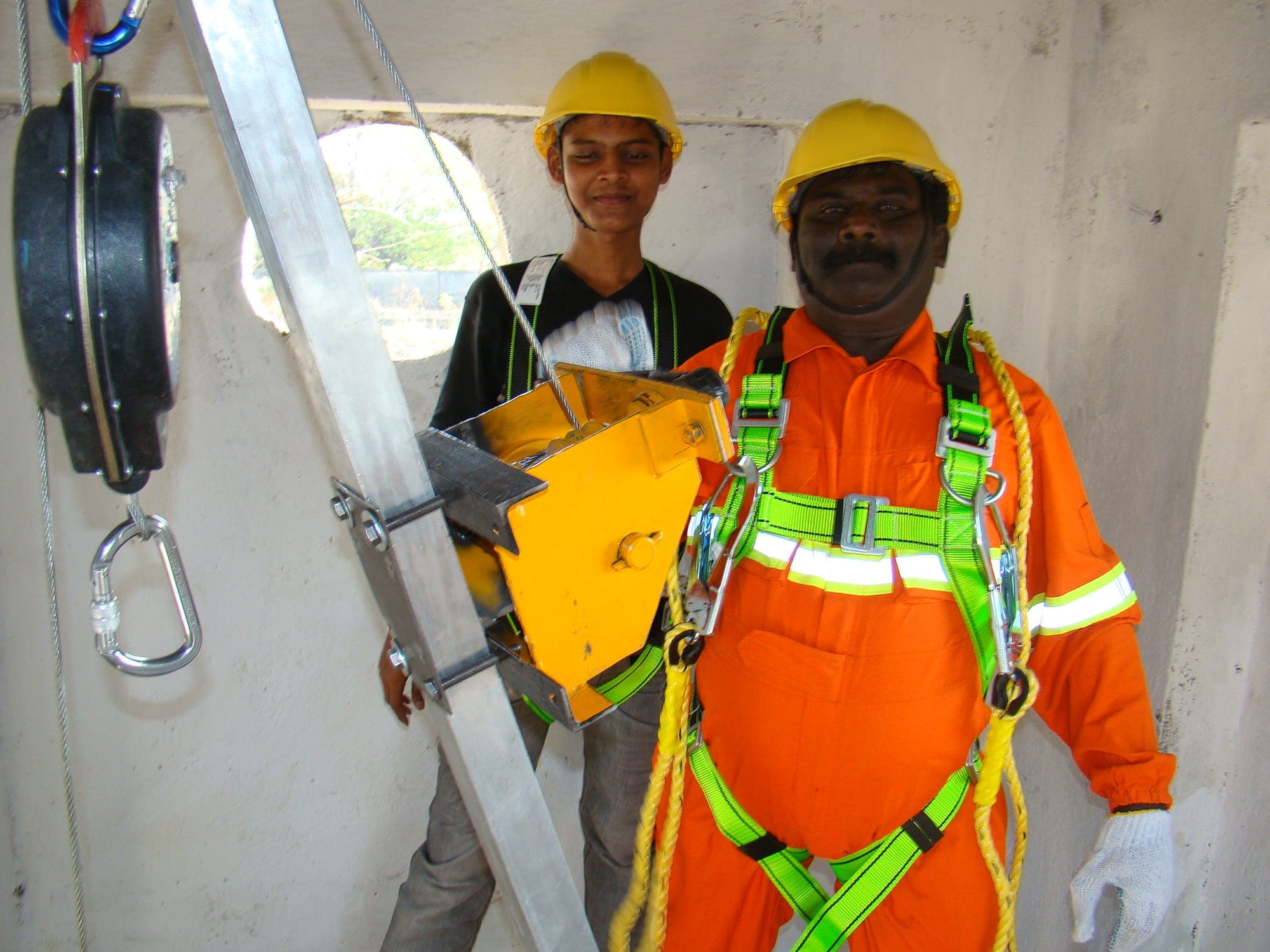 Two trainees checking a full body harness and ladder access equipment before entry