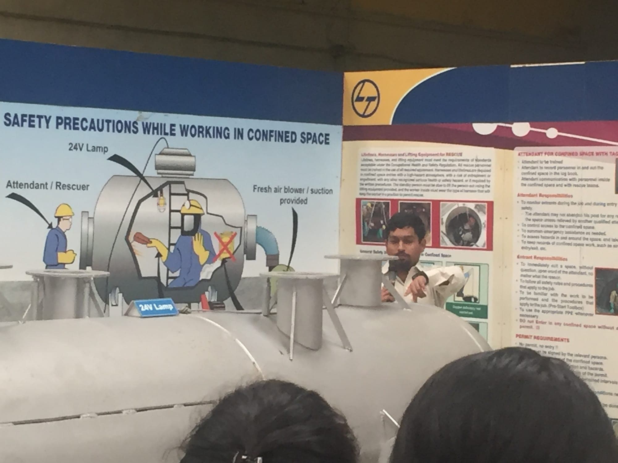 Trainer demonstrating confined space entry equipment beside a training vessel