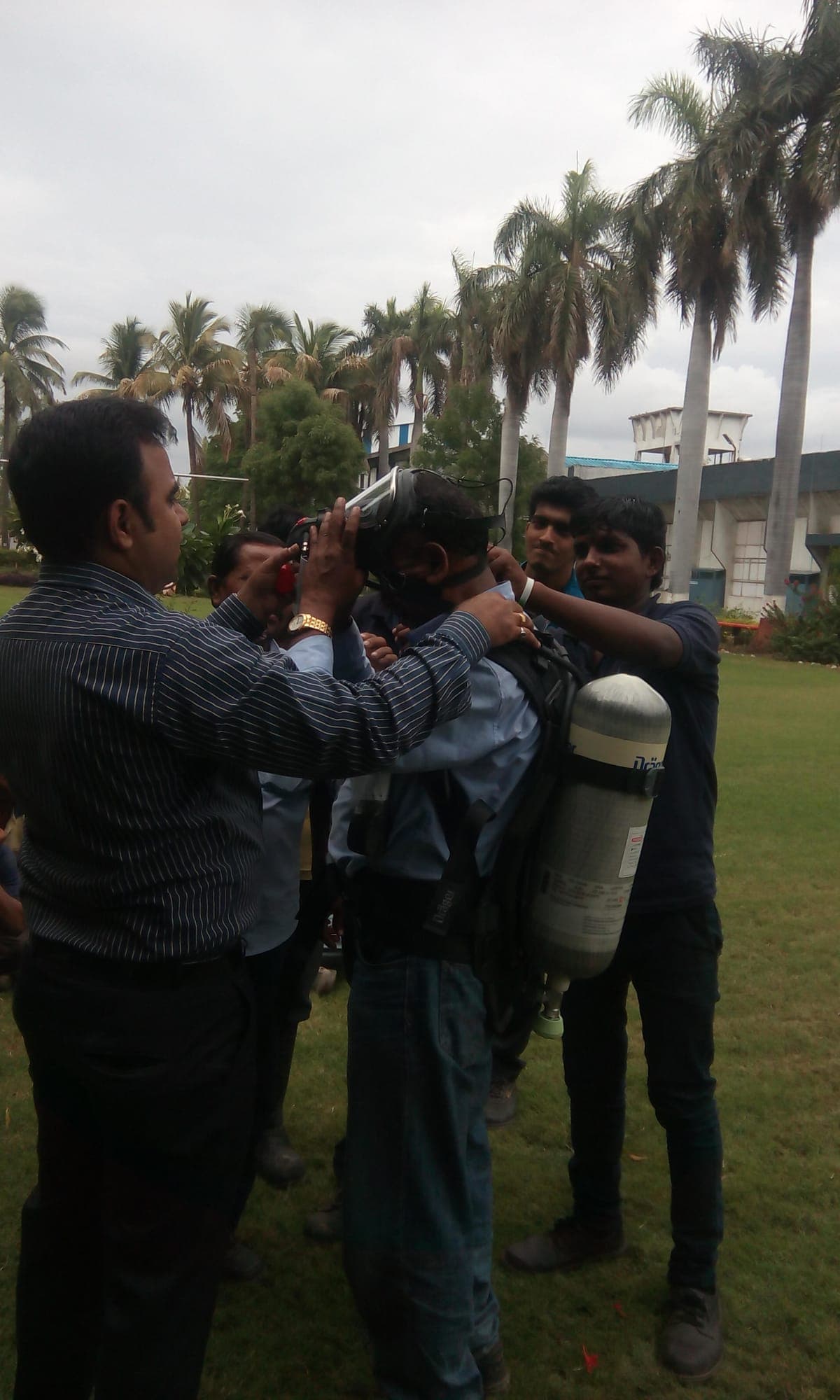 Trainer helping a participant don a self-contained breathing apparatus set outdoors