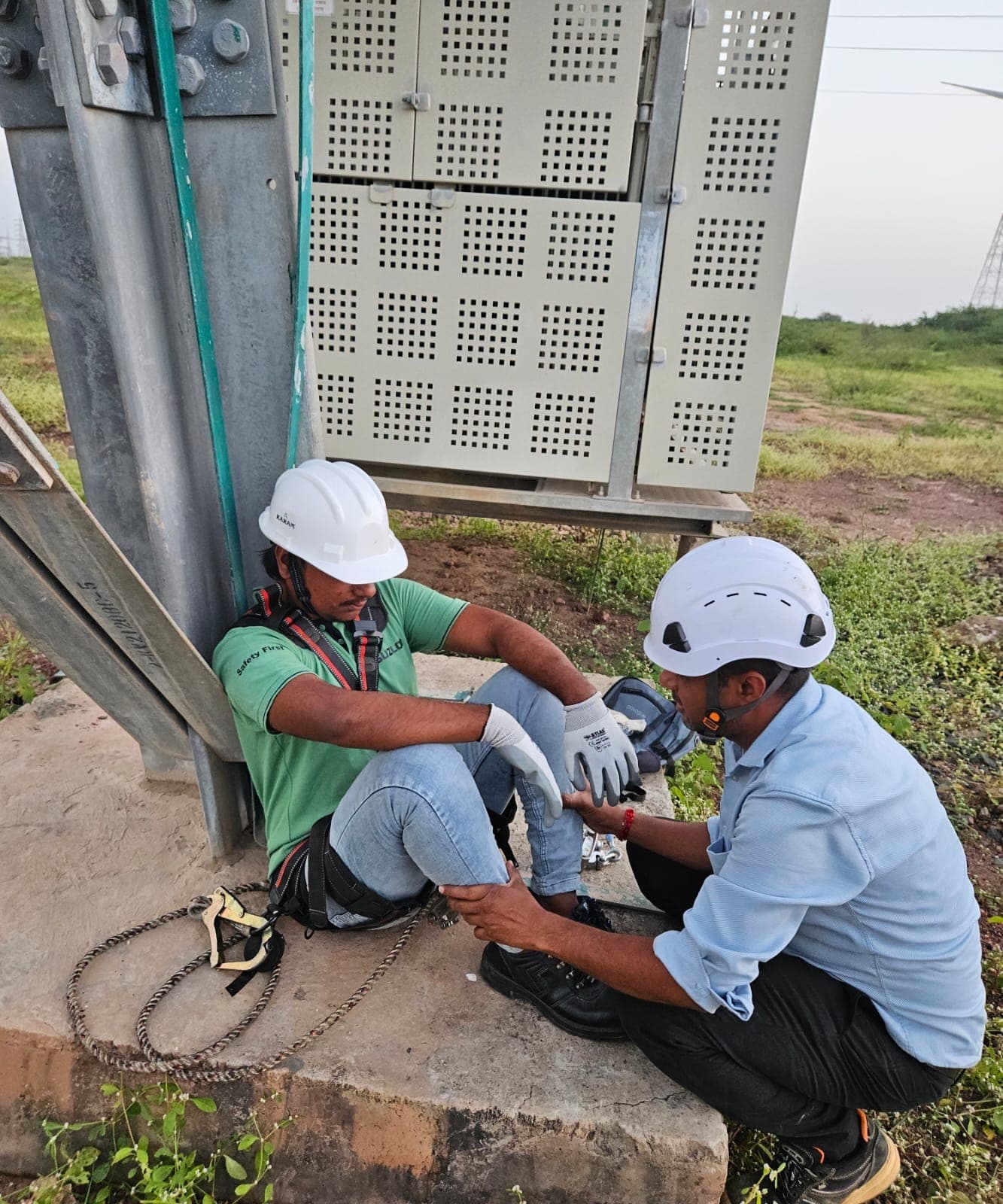 Two participants inspecting fall protection equipment on the ground before a climb