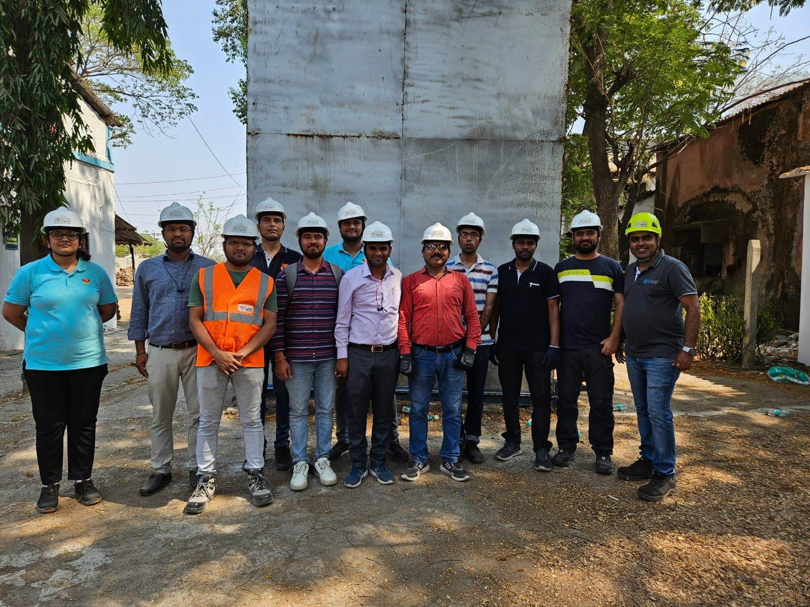 Group of fire safety course participants in hard hats standing outdoors at the practical area