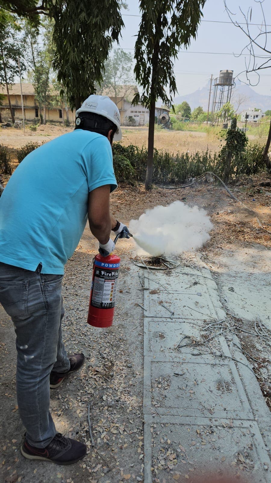 Trainee sweeping a fire extinguisher across the base of a training fire