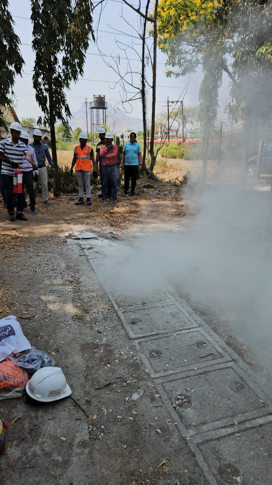 Participants tackling a training fire with an extinguisher as smoke rises from the tray