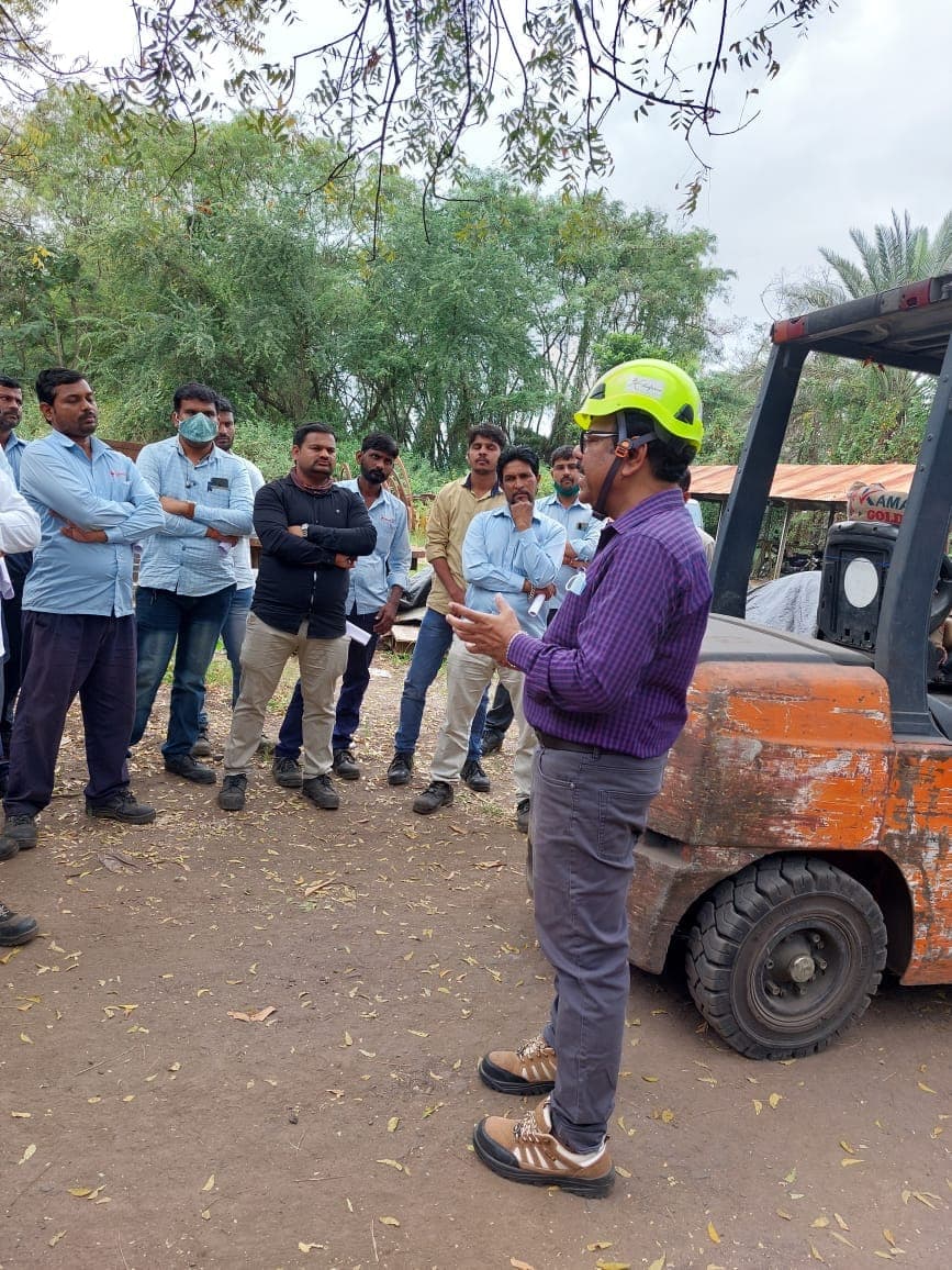 Trainer briefing a group of participants beside a forklift during forklift operations training