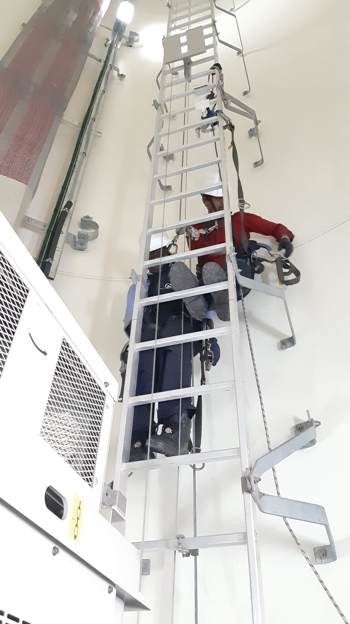 Rescuer rigging a rescue system on an internal service ladder during ladder rescue training