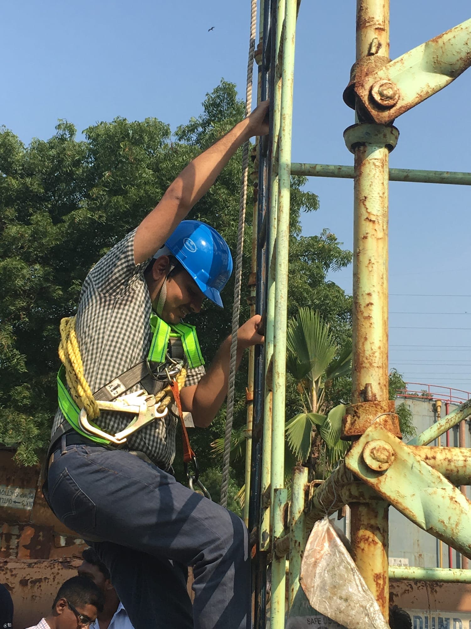 Trainee climbing a tubular scaffold in a harness with a lanyard clipped during work at height training
