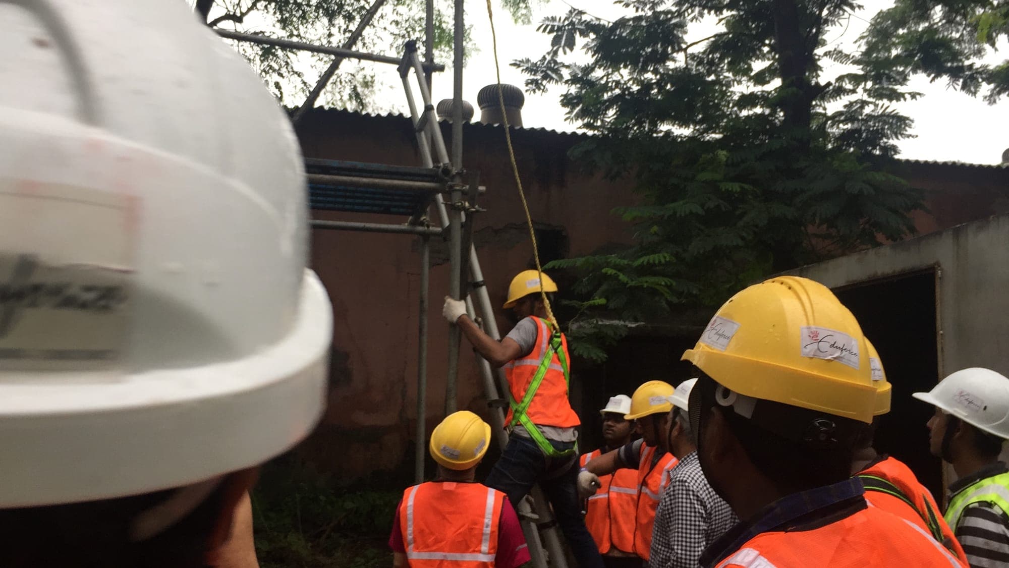 Participant tightening a scaffold coupler overhead during a practical scaffolding session