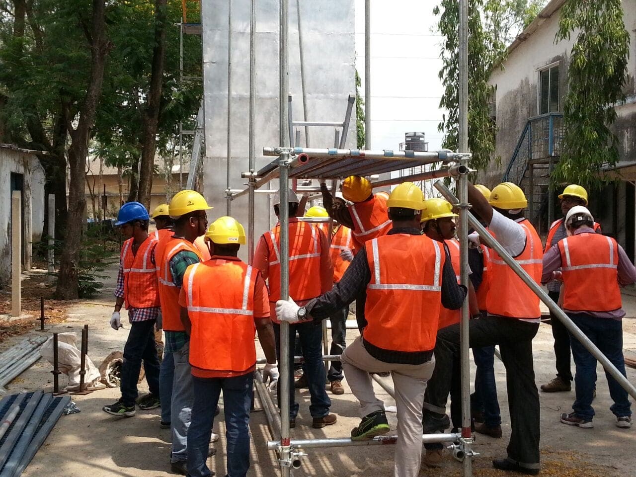 Participants gathered around a partly built scaffold during a practical training session