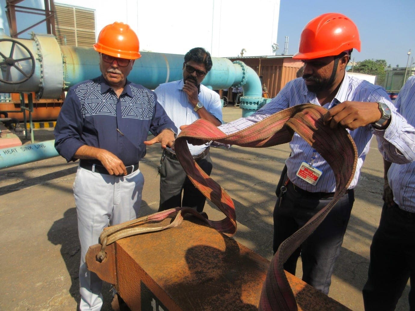 Trainers in helmets demonstrating webbing slings on a steel component