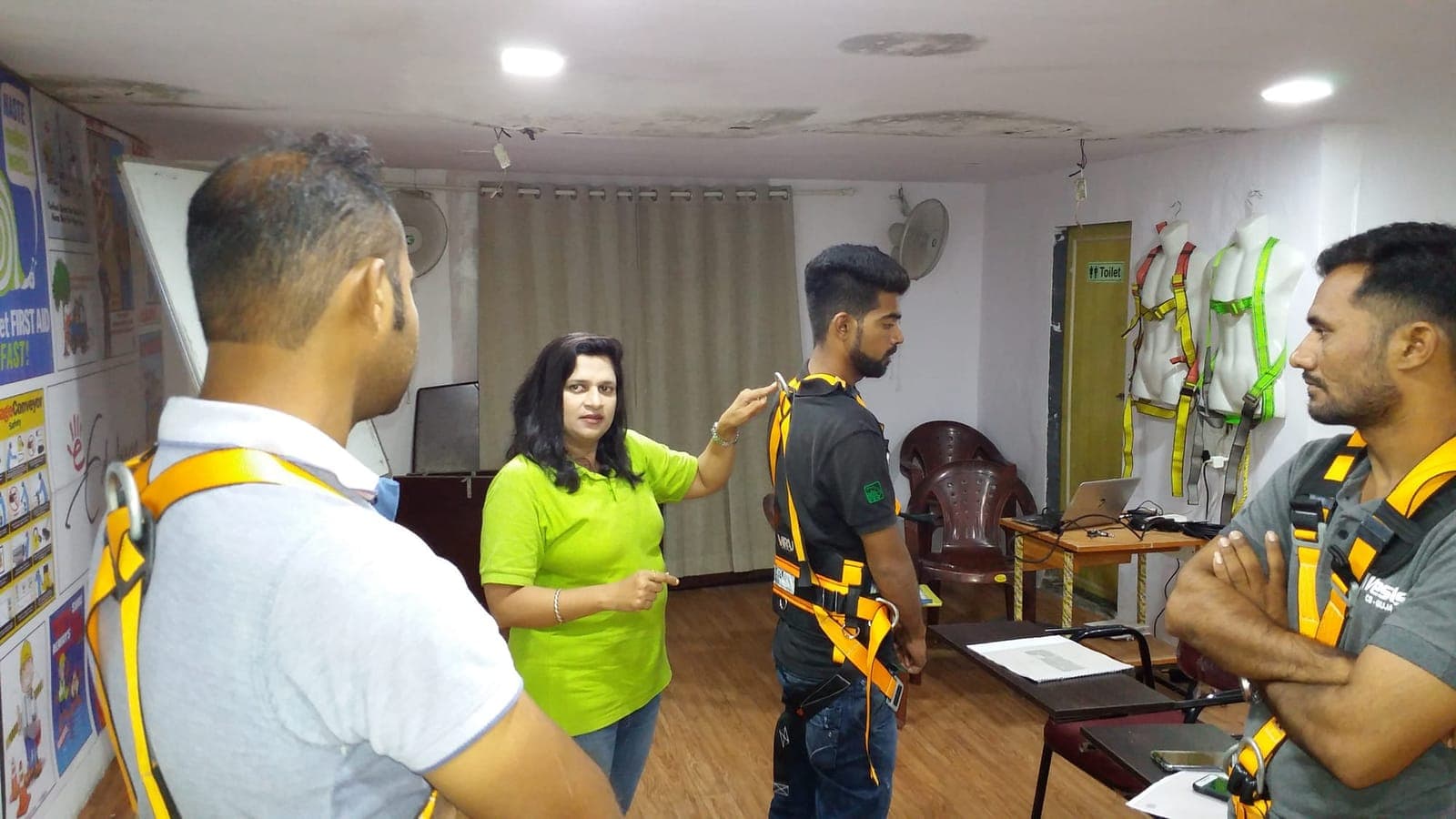 Trainer helping a participant fit and check a full-body fall-arrest harness during a working-at-height session
