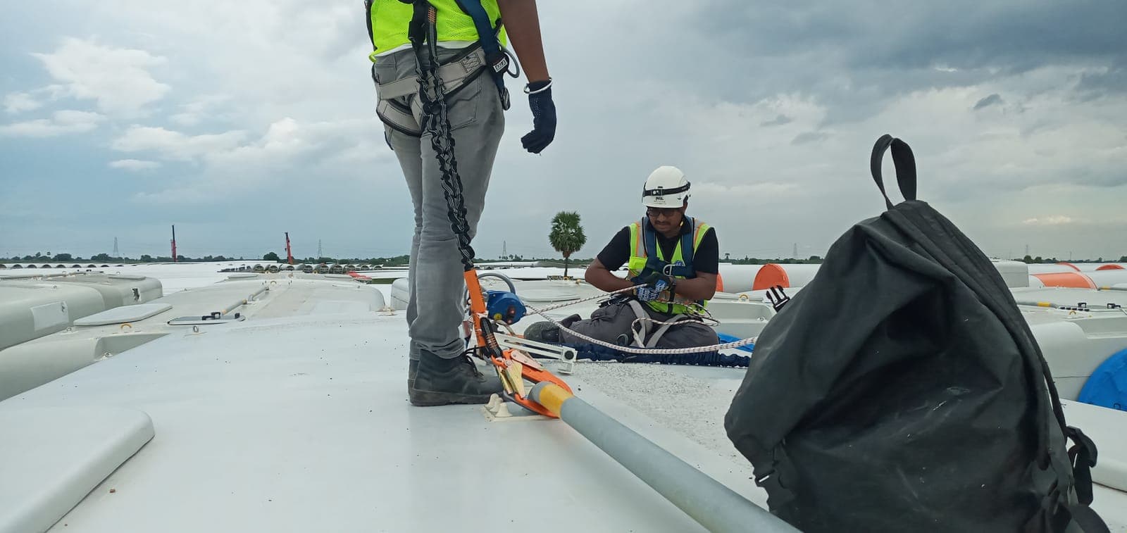 Technicians clipped to a safety line on the roof of a wind turbine nacelle