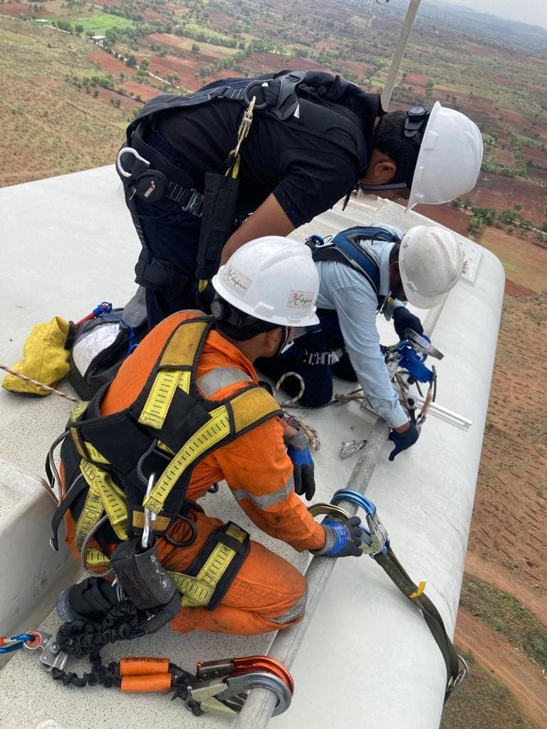 Technicians in harnesses carrying out a rescue exercise on the roof of a wind turbine nacelle