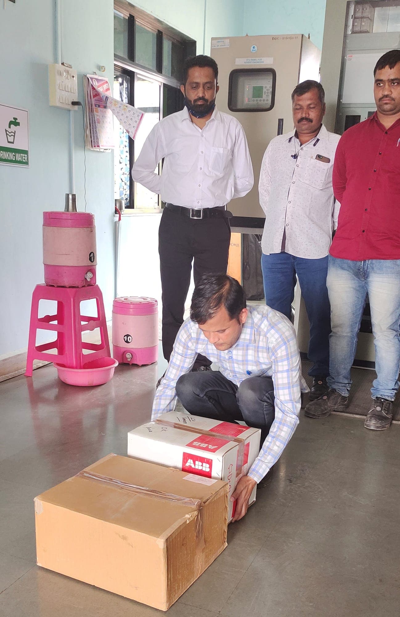Participant crouching to lift a carton from the floor with a straight back while a group observes during a manual handling session