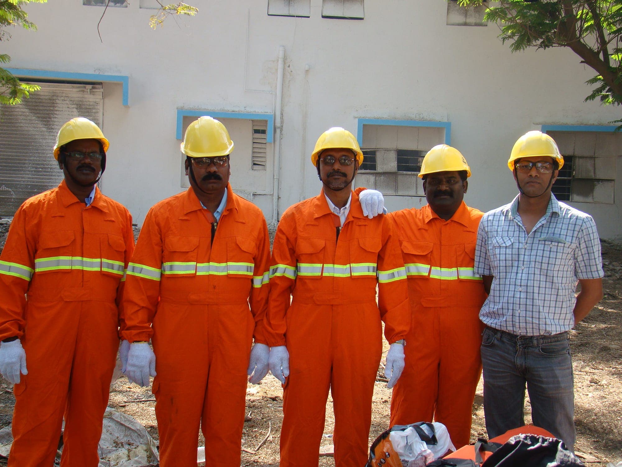 Group of confined space training participants in orange coveralls, hard hats and gloves before a practical session
